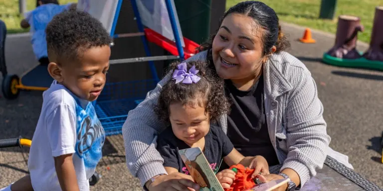 A teacher reading a book to two young children